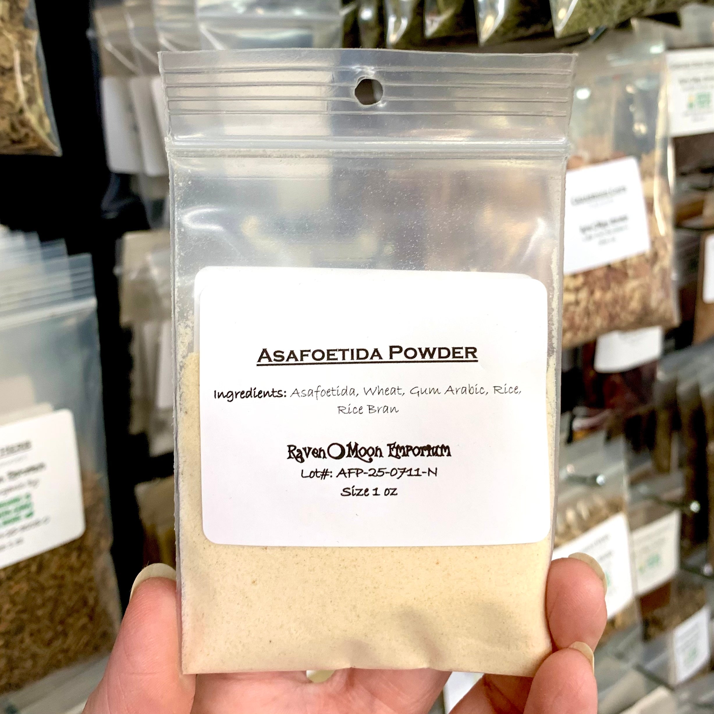 Asafetida powder in a clear zip plastic bag. The label lists the ingredients: Asafeotida, wheat, gum arabic, rice, and rice bran.