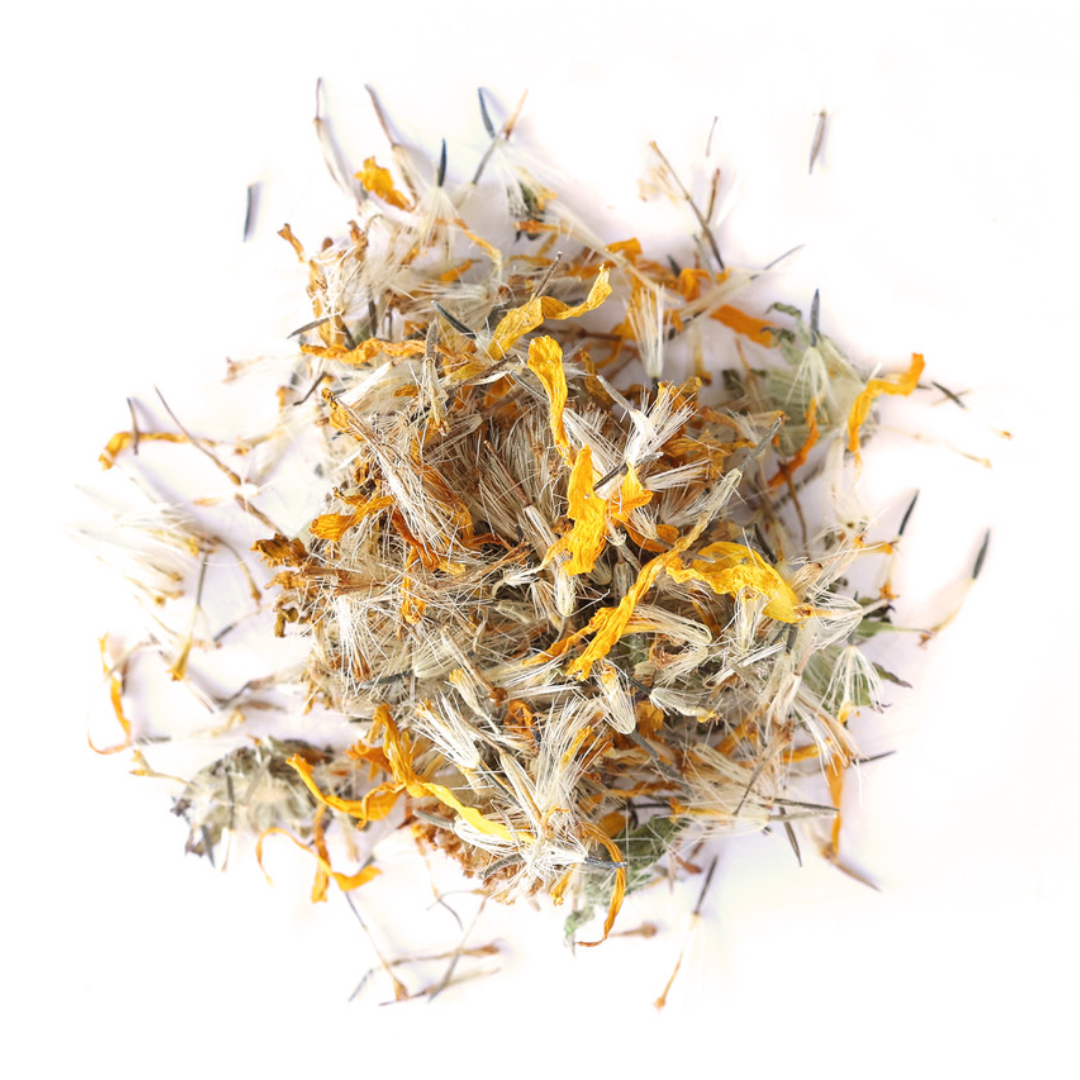 A close-up shot of a pile of dried Arnica montana flowers against a white background. The flowers are a vibrant yellow-orange, and the seeds are a mix of white and tan. The image is well-lit and shows the texture of the dried plants.
